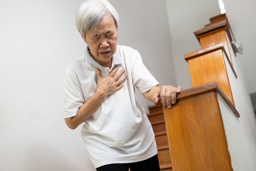 older asian woman clutching at chest