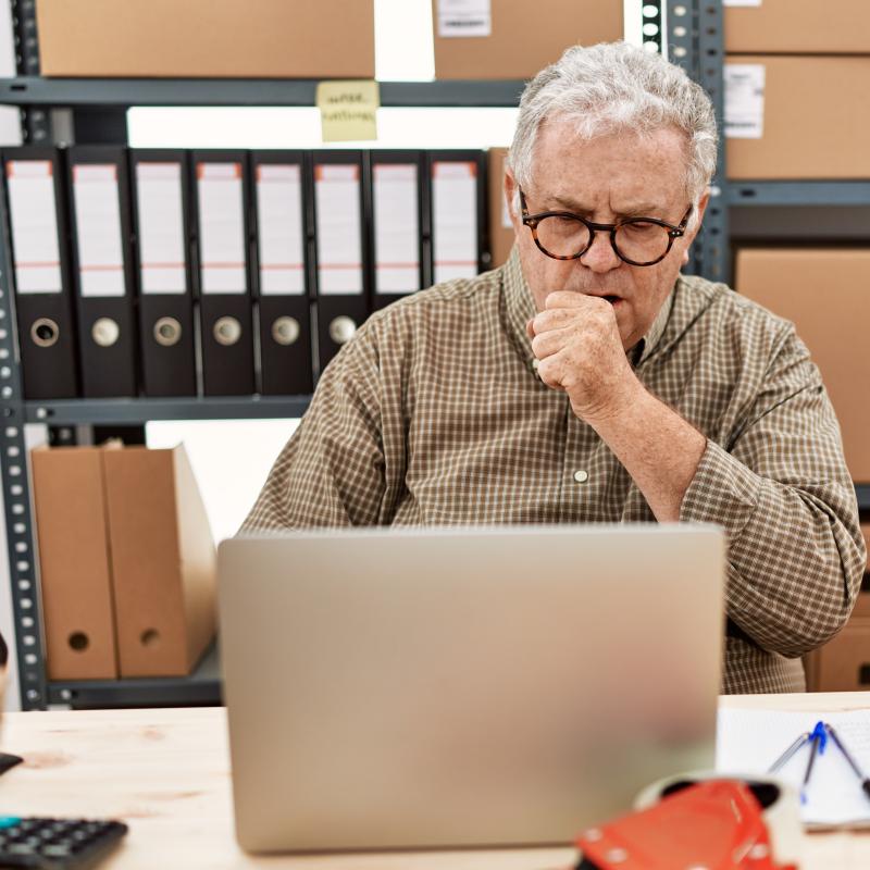 Man coughing at desk