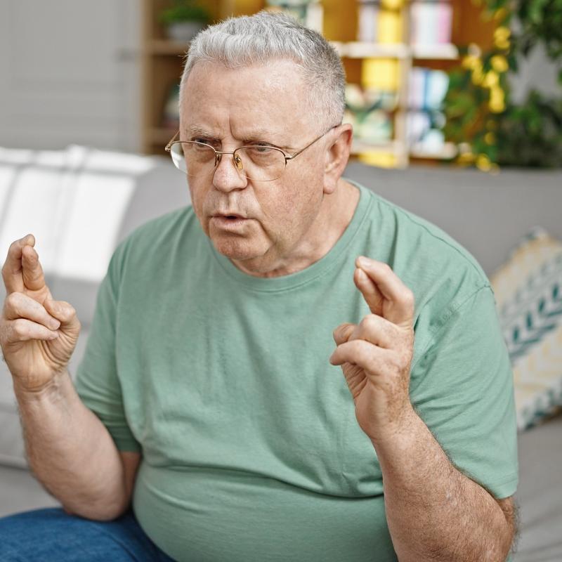 older man with fingers on both hands crossed