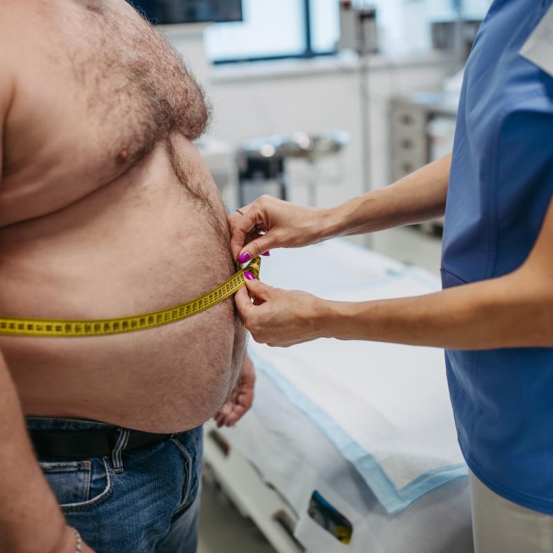 Obese man having his waist circumference measured